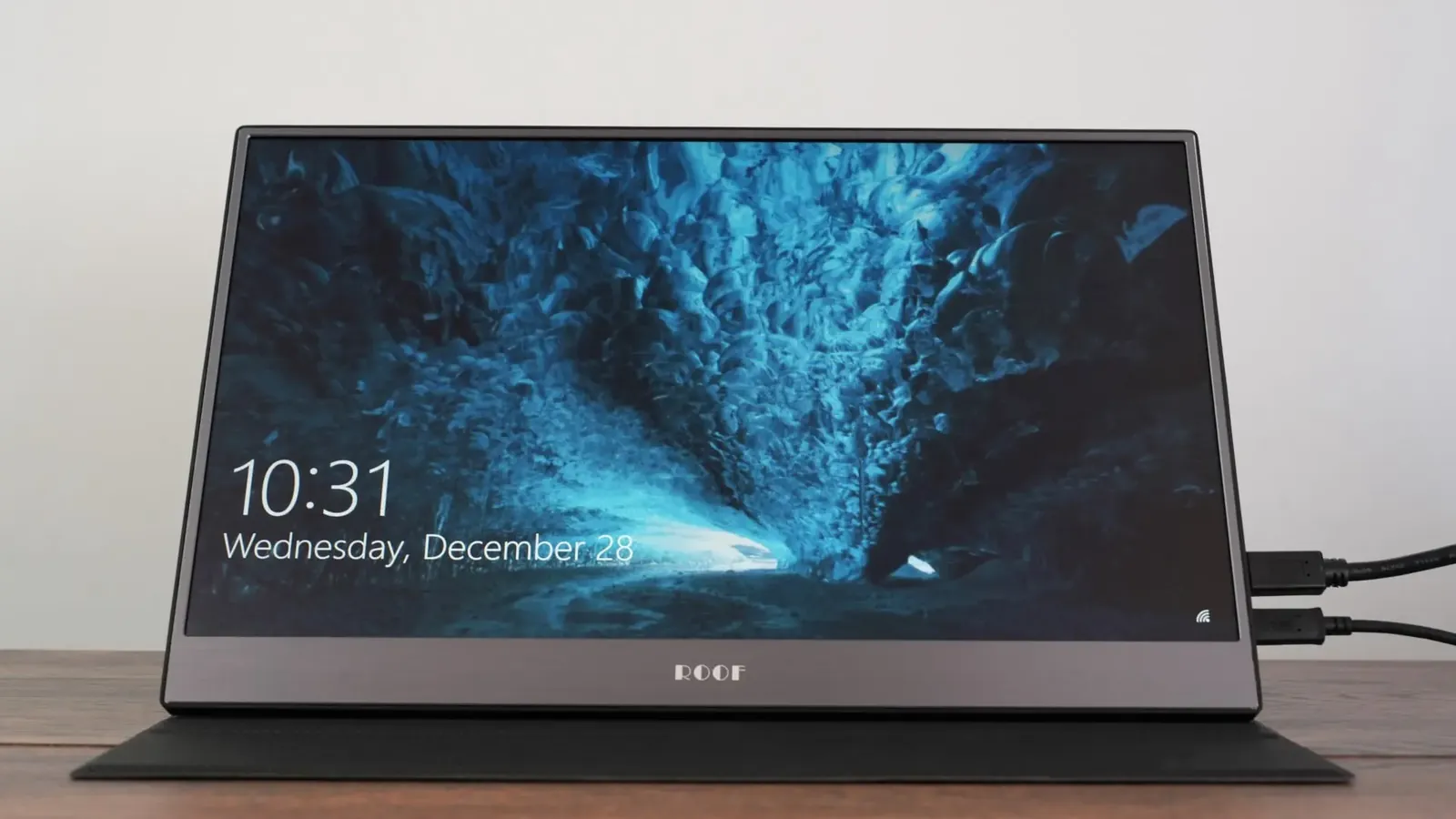 15.6 inch portable touchscreen monitor standing on its foldable cover showing the Windows lock screen